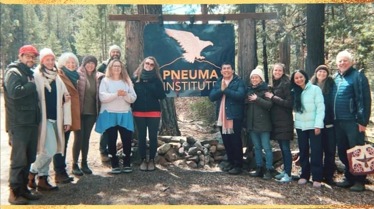 The Pneuma Canada community gathered beneath the Pneuma Institute sign at a forest retreat center